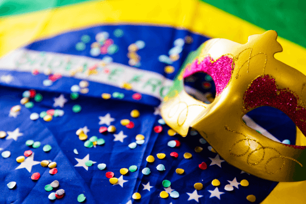 Bandeira do Brasil com confetes e máscara de carnaval.