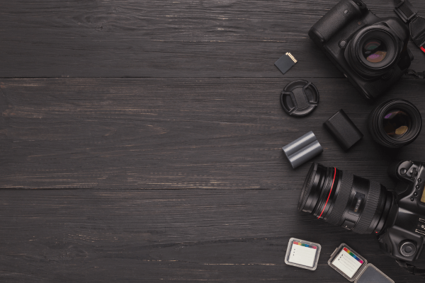 Equipamentos de fotografia sobre mesa escura.