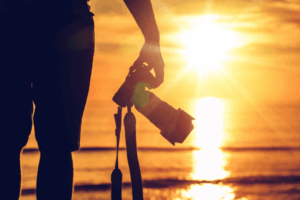 Pessoa com câmera fotográfica ao pôr do sol.